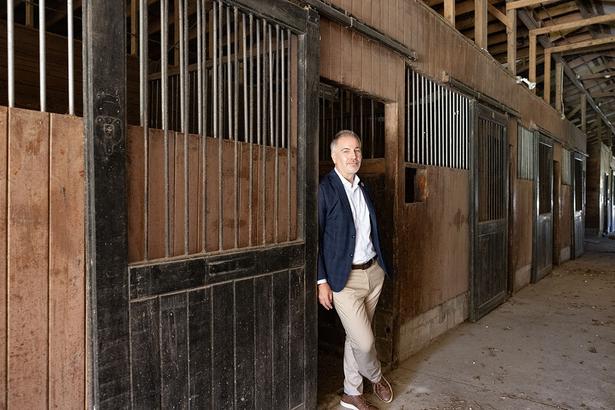Marc Orlando in Sport Coat in the horse paddocks leading on door