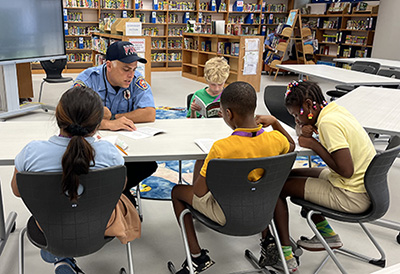 Firefighter reading with students in library