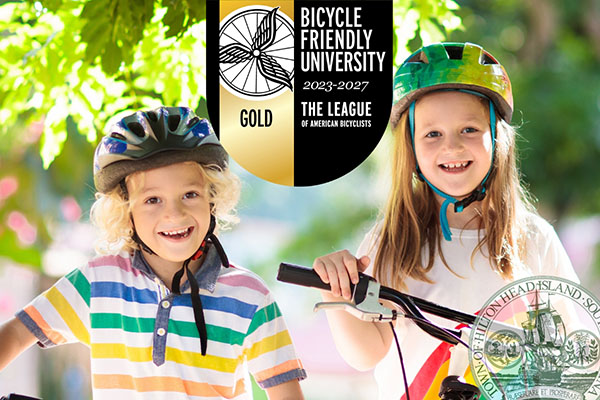 Two gils in bicycle helmets with bicycle friendly community logo overlay