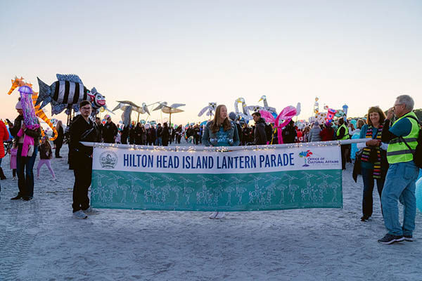 Participants holding Latern Parade Banner at start of parade on the beach