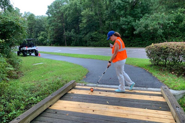 Town employee measuring pathway bridge entrance