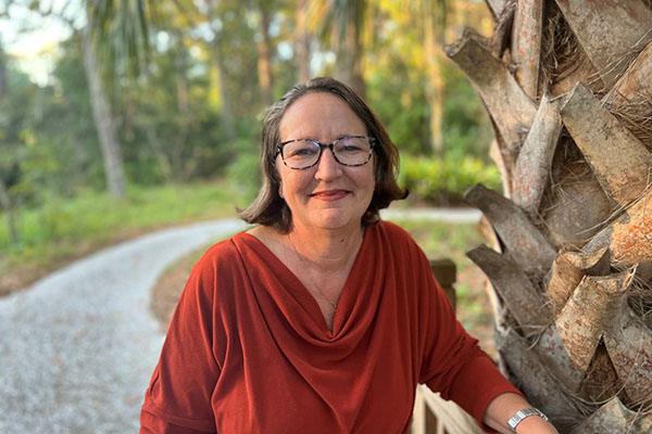 Natalie Harvey standing next to a palm tree in front of path