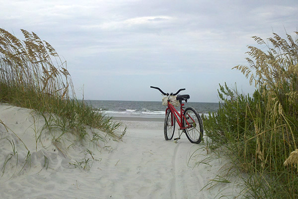 Red bike parked in sandy beach access with view of ocean
